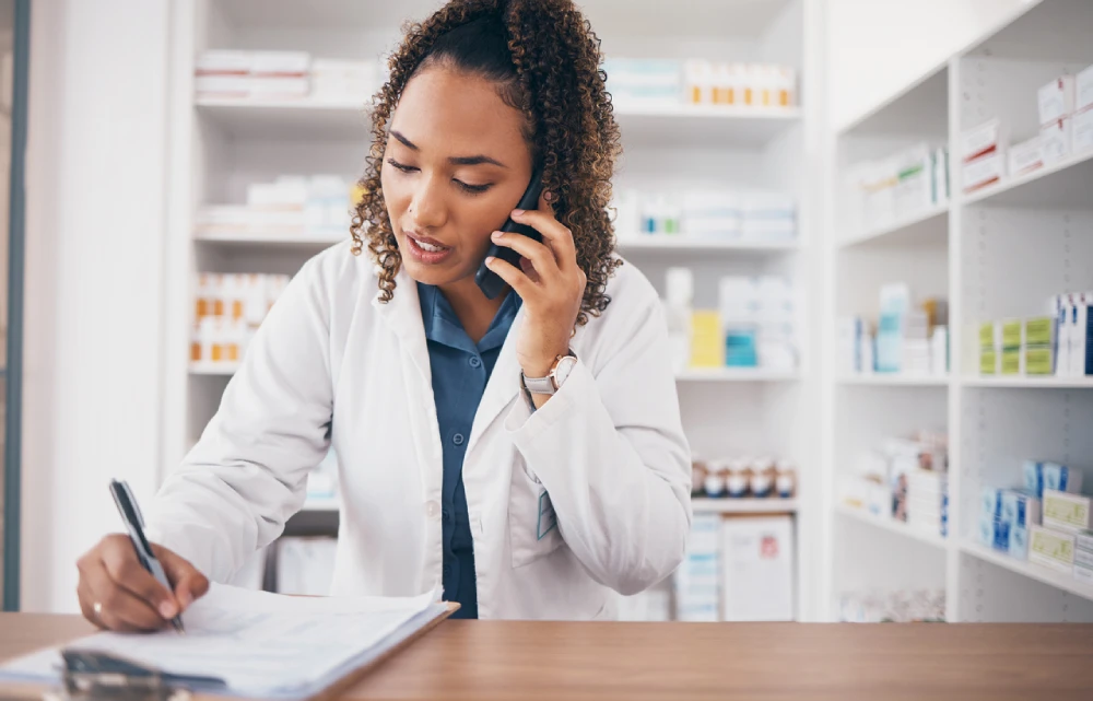 female pharmacist on the phone with distributors of their products to support pharmacy supply chain management success