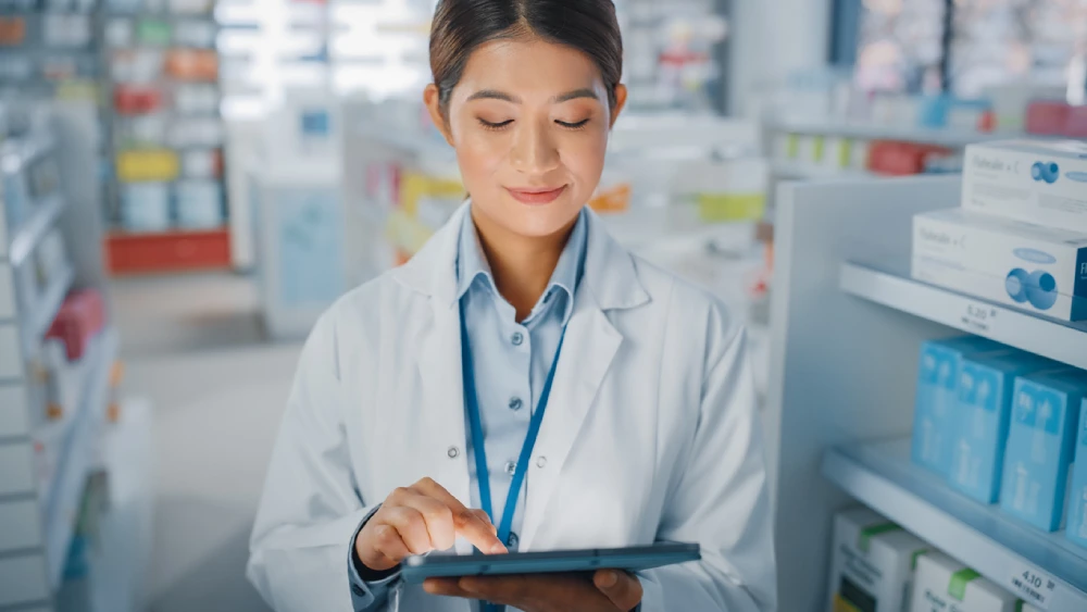 female pharmacist tracking inventory on a tablet to support pharmacy supply chain management strategies