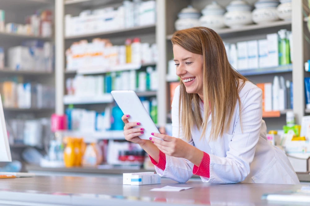 pharmacist smiling at her phone - checking her pharmacy online growth