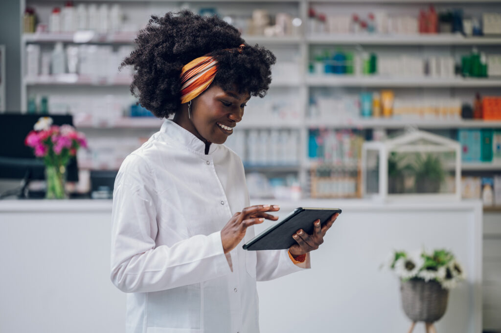 A female pharmacist is scrolling through a tablet.