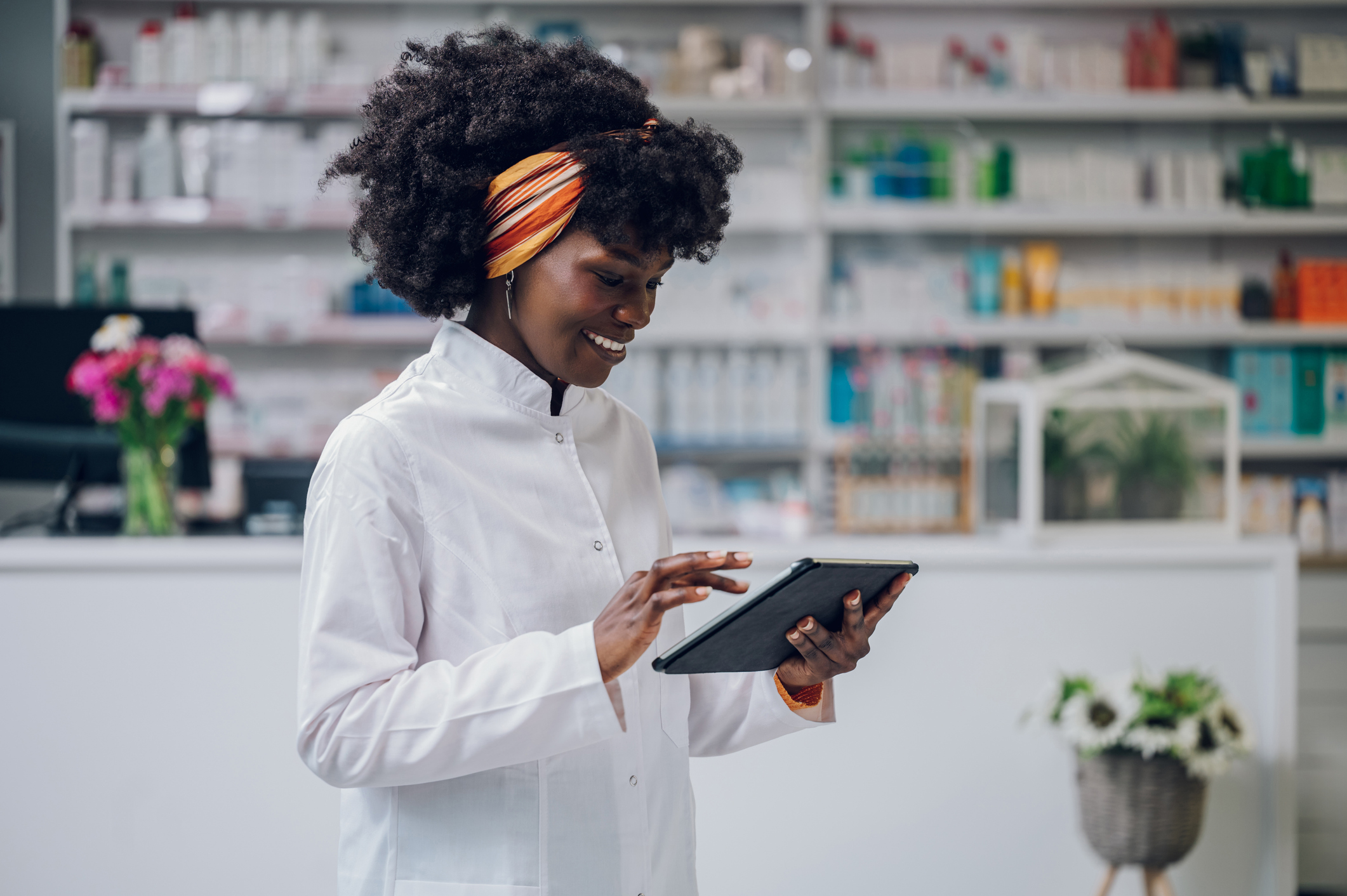 A female pharmacist is scrolling through a tablet.