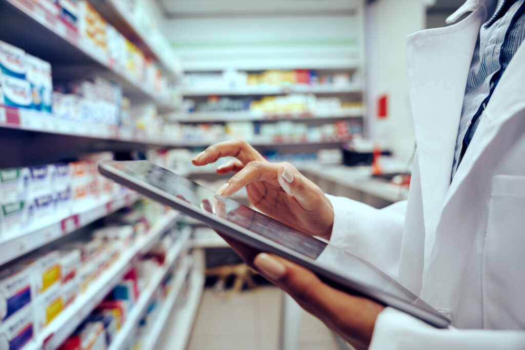 Close up of a pharmacist's hands scrolling a tablet in a pharmacy.
