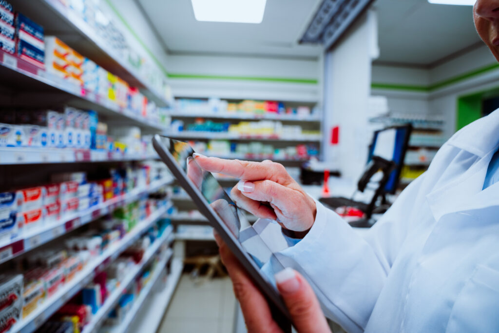 A female pharmacist reviews a tablet while taking inventory. 