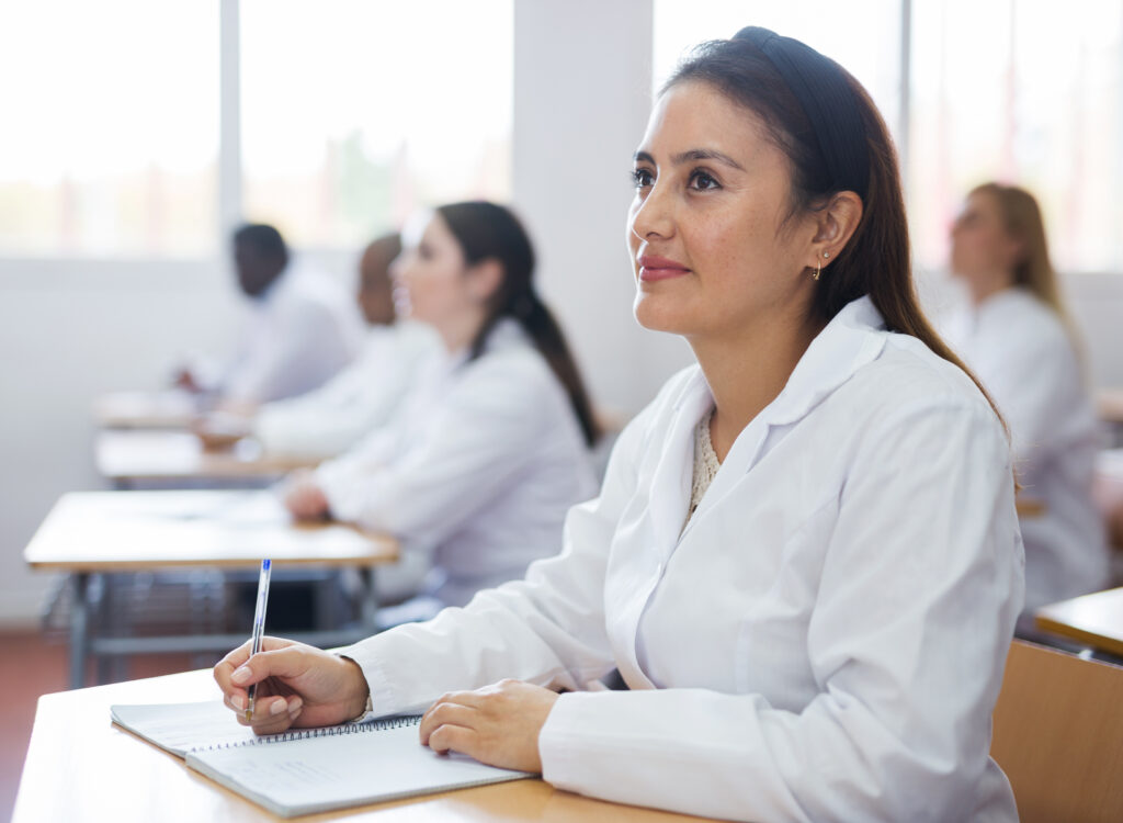 A female pharmacy student sits in a classroom with classmates.